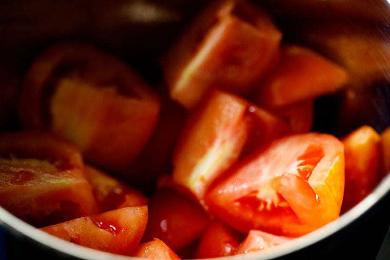 Fresh tomatoes cut into wedges in the base of a blender.