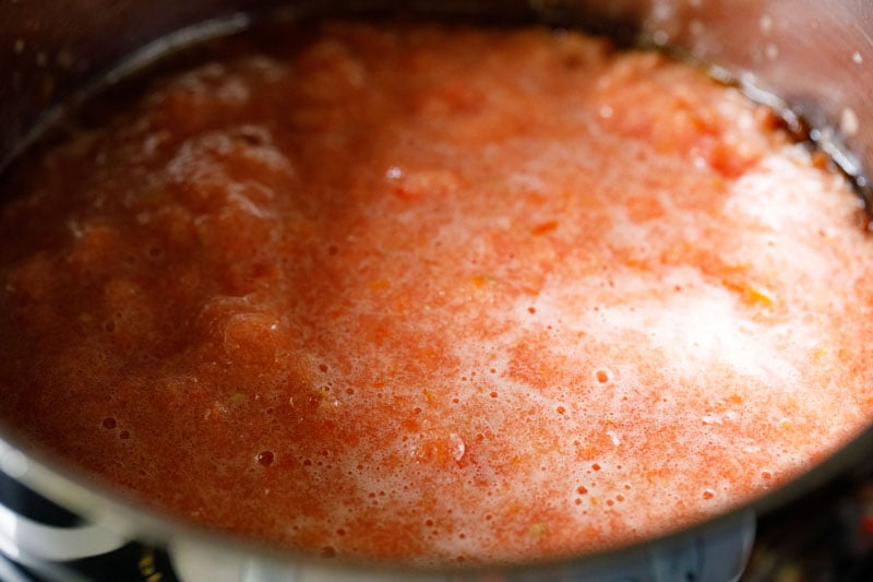 Crushed tomatoes added to skillet with caramelized onions.