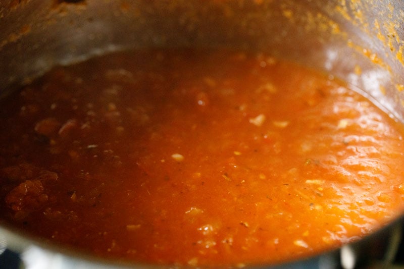 Marinara sauce thickening and simmering in the skillet.