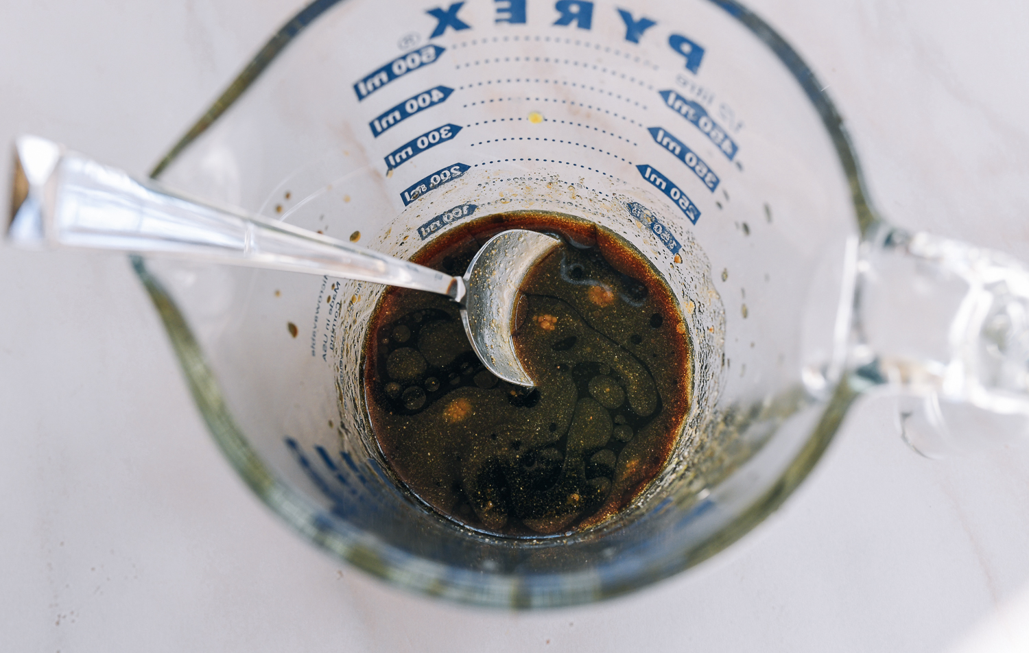 Sauce mixture for stir-fry in measuring cup with spoon