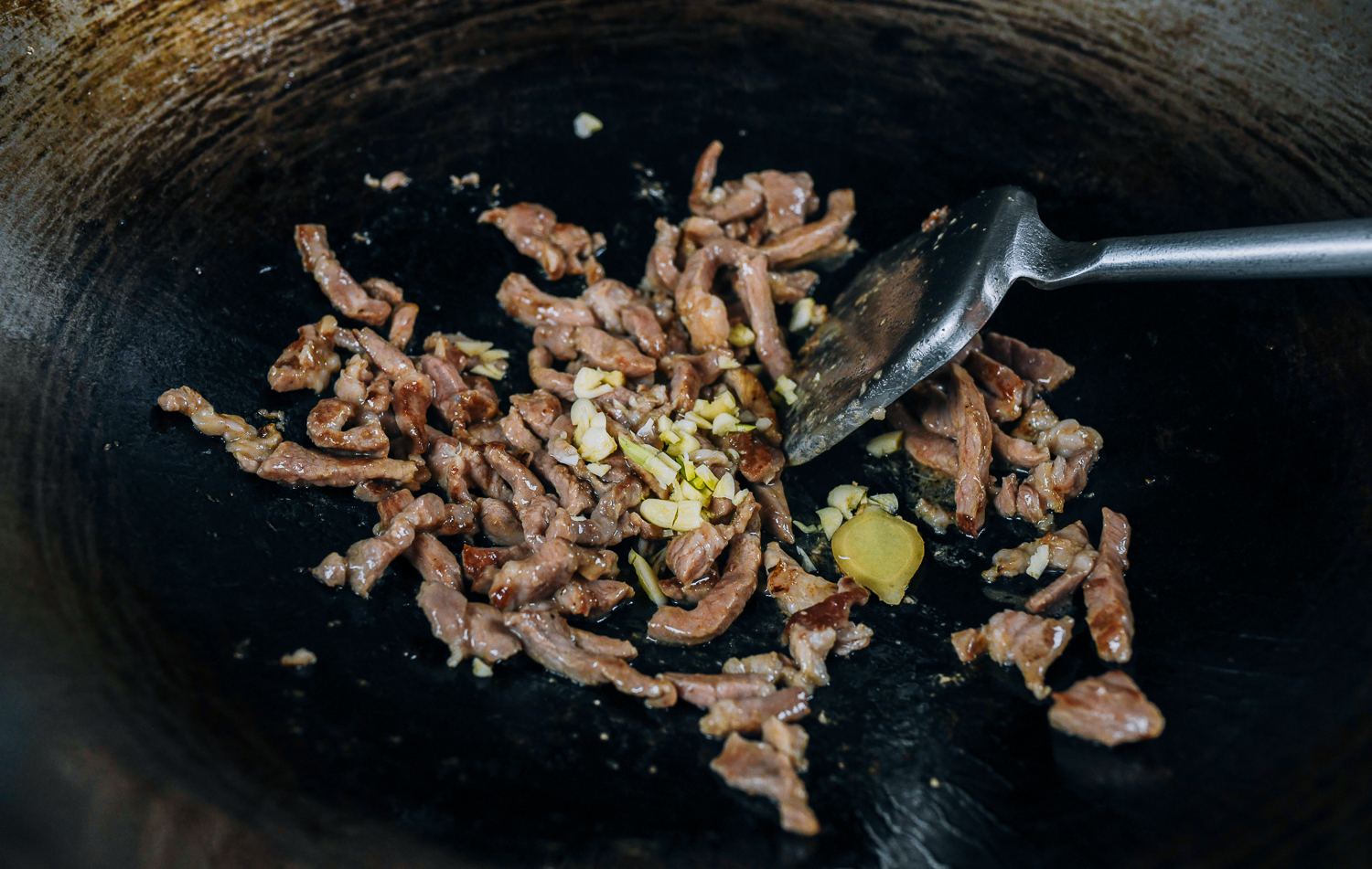 Ginger and garlic added to pork in wok