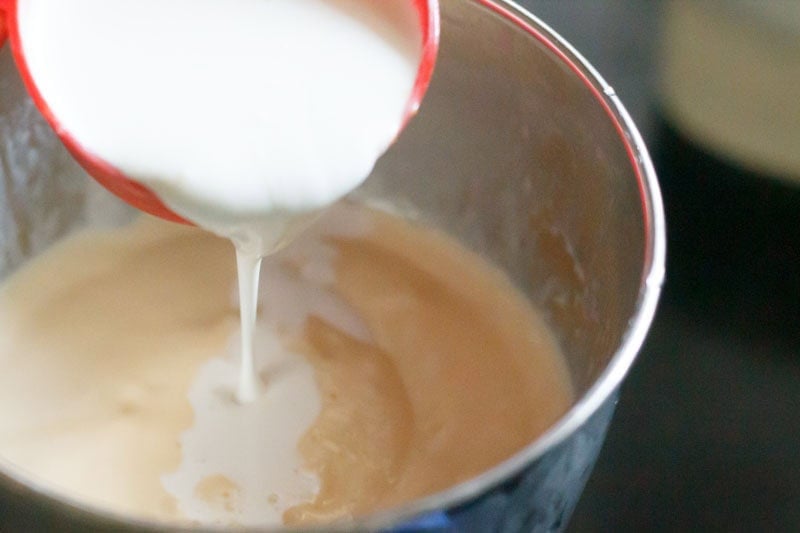 Cream being poured in the blender with a red measuring cup.