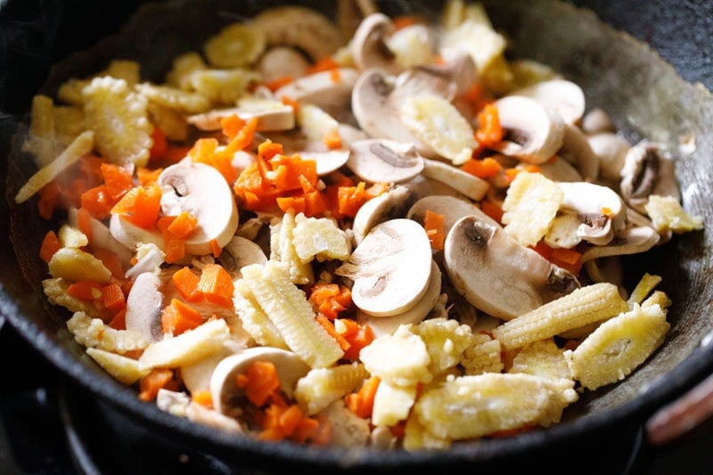 Sliced mushrooms, finely chopped carrots, and sliced baby corn added to the pan.