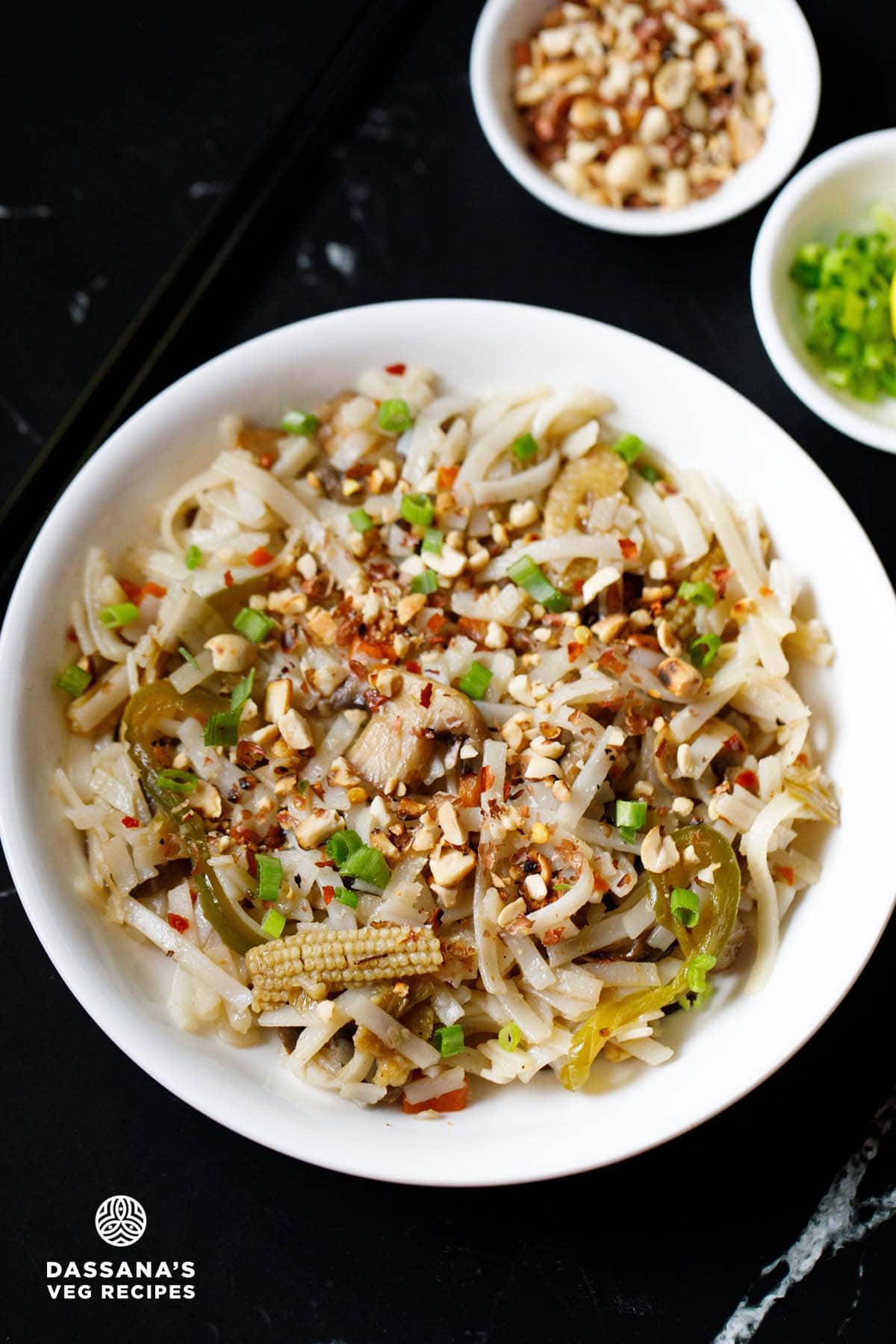 Pad Thai in a white bowl garnished with crushed peanuts and spring onions.