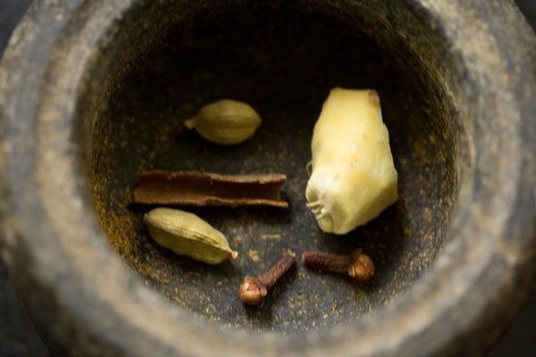 Cinnamon, green cardamoms, cloves and ginger in a mortar