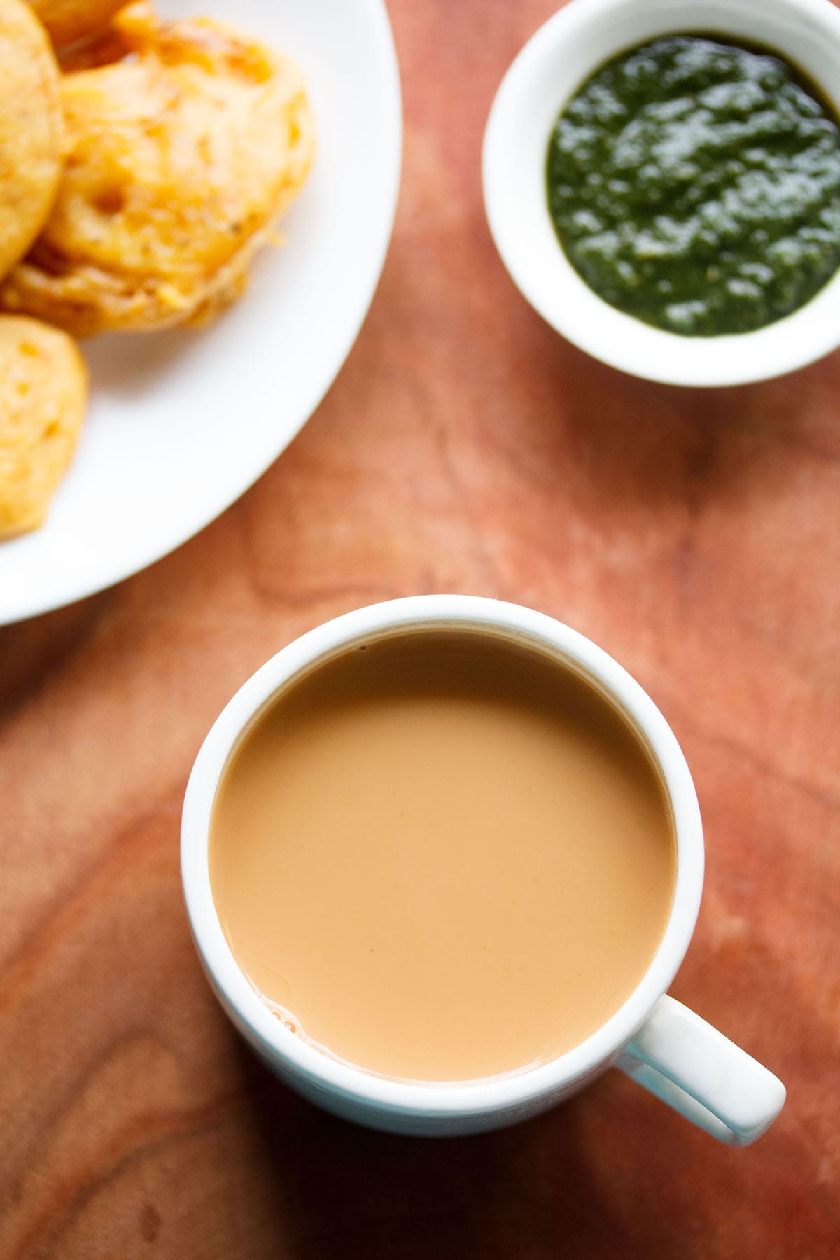 Overhead shot of masala tea in a white cup on brown board