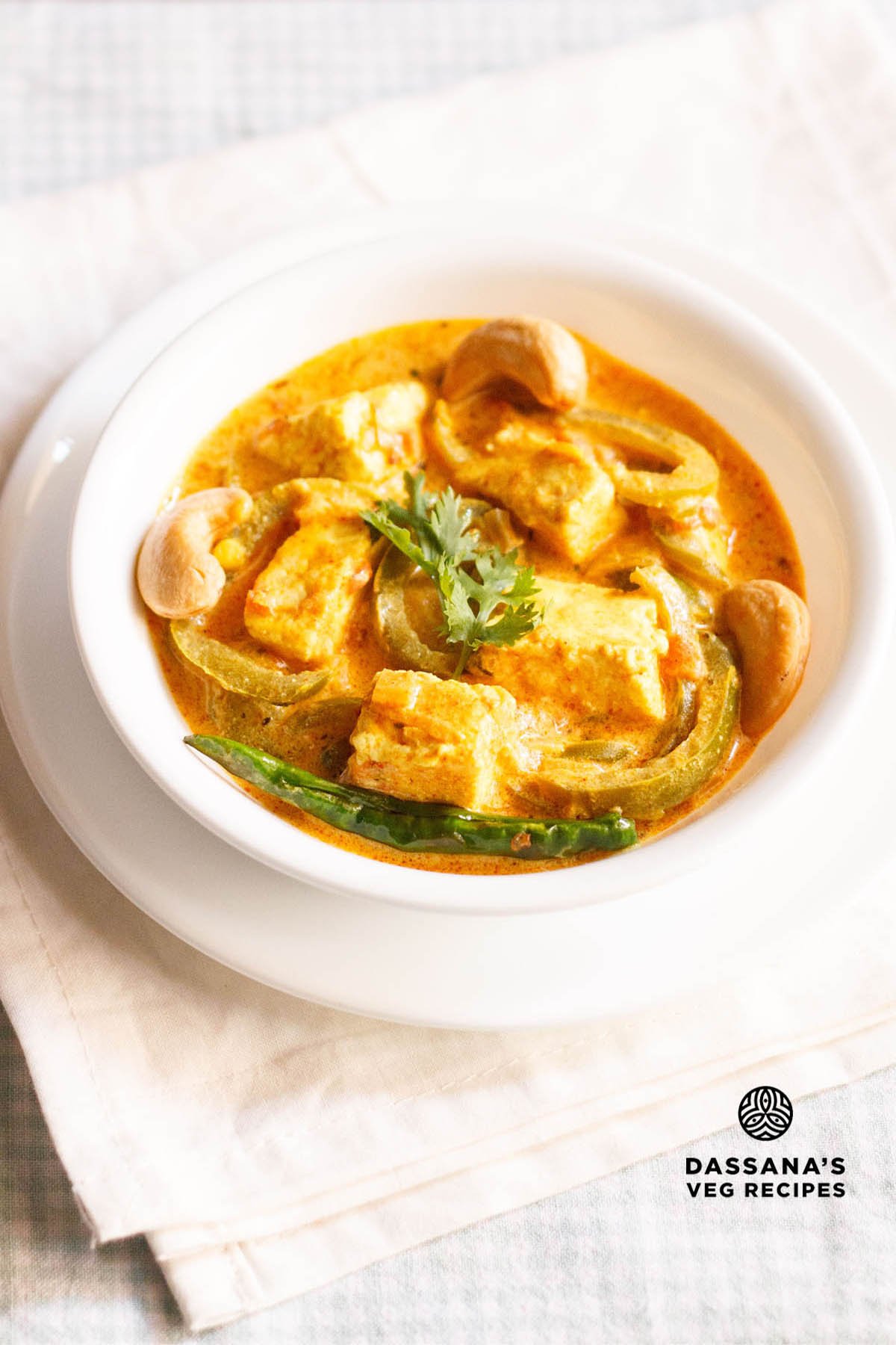 Paneer Sabji in a white bowl on an off-white colored folded napkin.