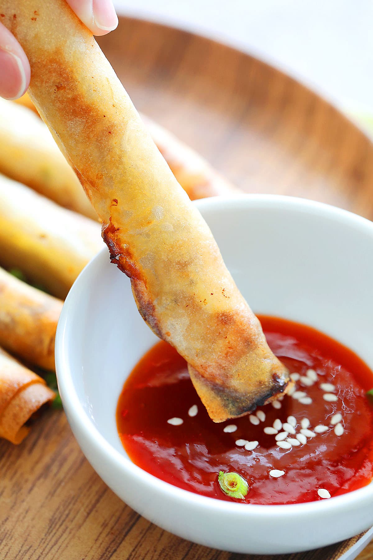 Crispy lumpia half-dipped in spicy chili sauce.