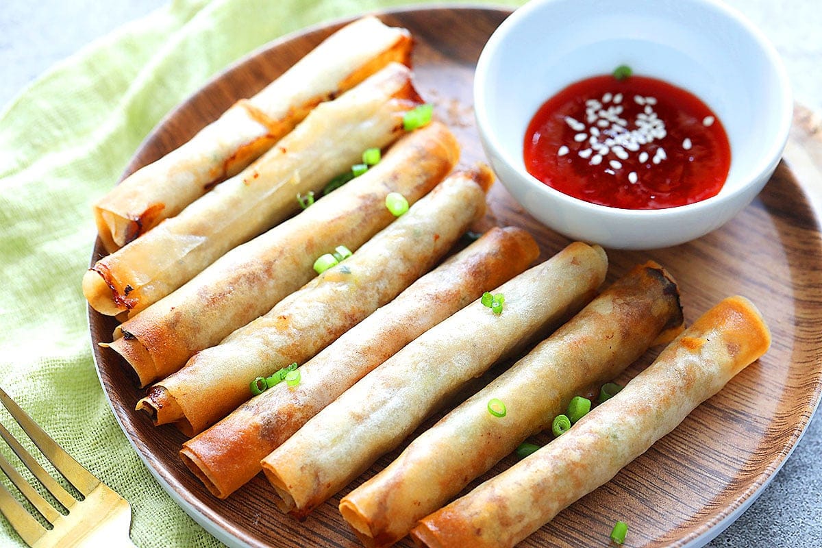 Air Fryer Lumpiang Shanghai on a plate with a side of chili sauce for dipping.