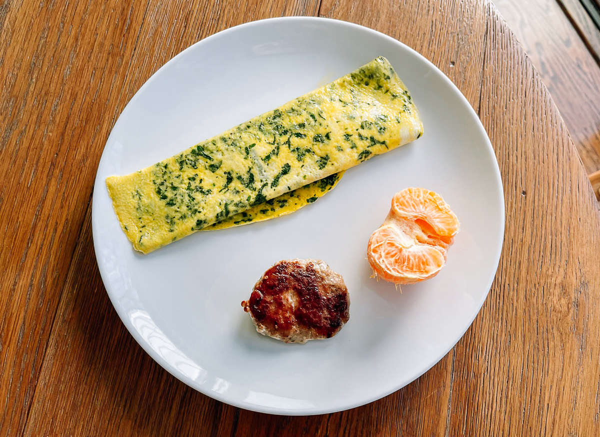 Spinach omelet, sausage patty, and clementine