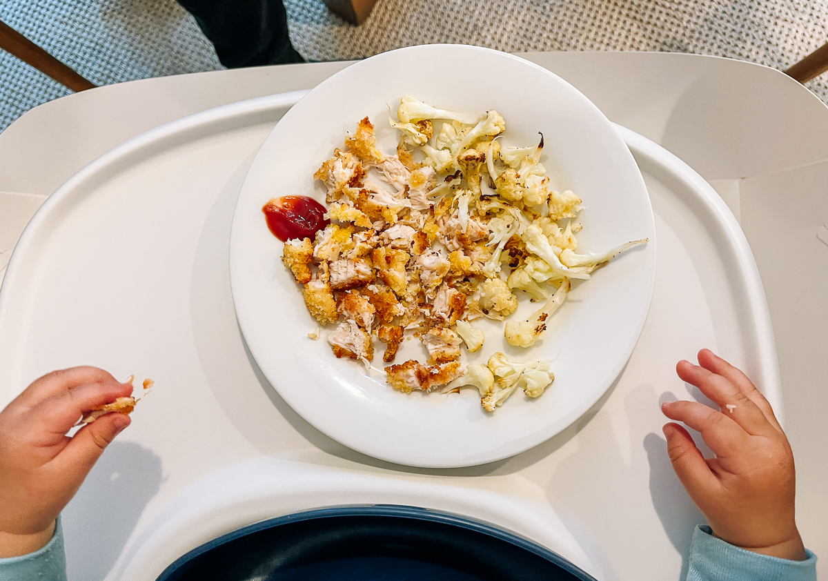 Air fryer chicken tenders with ketchup, roasted cauliflower cut into small pieces for toddler