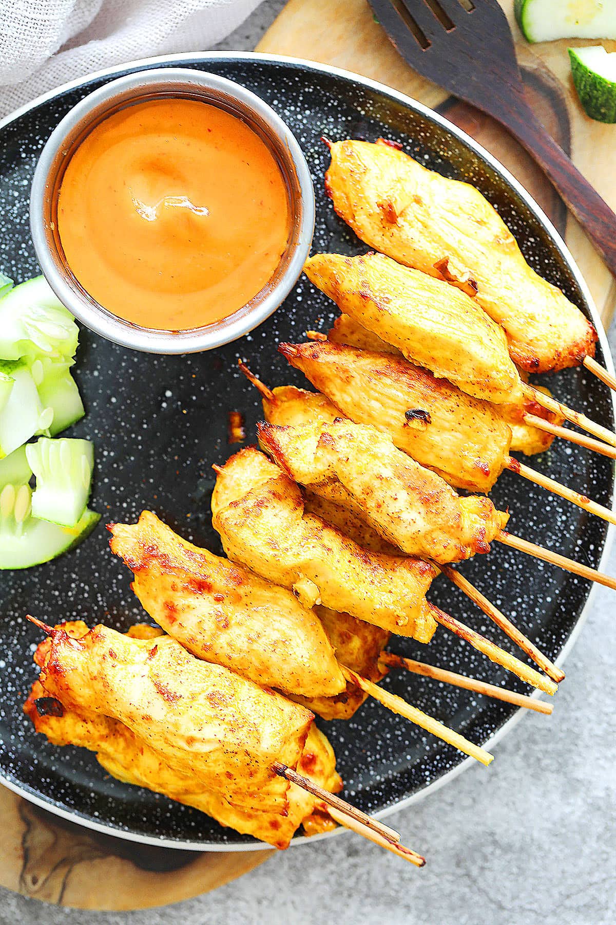 Juicy air fryer Thai chicken satay skewers with golden edges, served with fresh cucumber slices and homemade Thai peanut satay sauce.