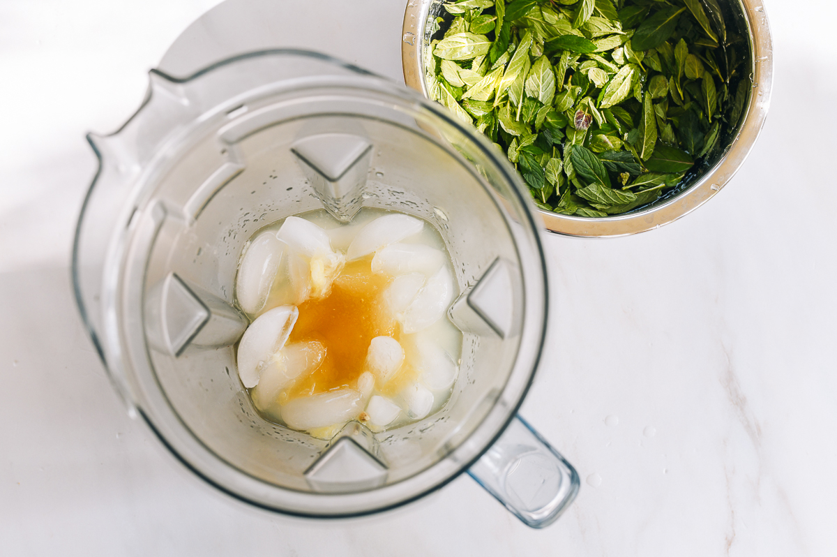 Ingredients in blender next to bowl of mint